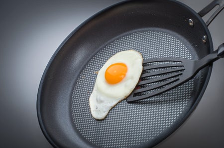 Fried egg in pan with black plastic spatula