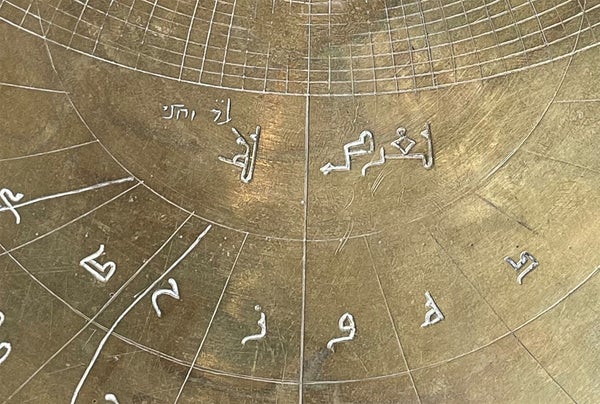 Close up of the Verona astrolabe showing Hebrew inscribed (top left) above Arabic inscriptions. Inscriptions are carved into metal