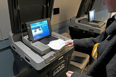 A voter placing their ballot in an tabulation machine in a polling place in Provo, Utah