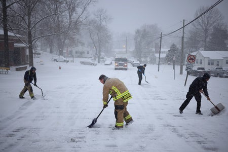 Firefighters with Louisville Fire Department Quint 9 shovel snow from the street in front of their station during a winter storm on January 5, 2025 in Louisville, Kentucky