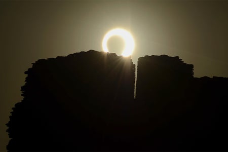 The moon appears to cover the sun during an annular eclipse just above and behind an ancient building at Chaco Culture National Historical Park