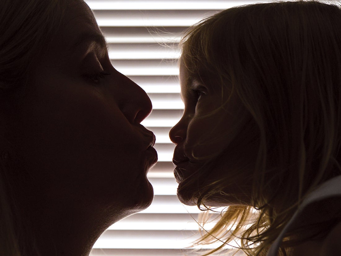 A woman leans in to kiss a child