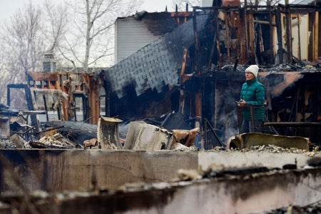 Woman surveying burnt down apartment complex .