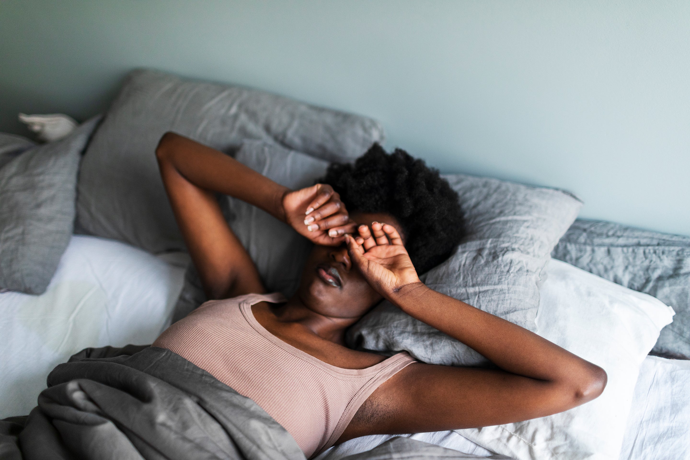 Woman rubbing eyes in bed struggling to wake up