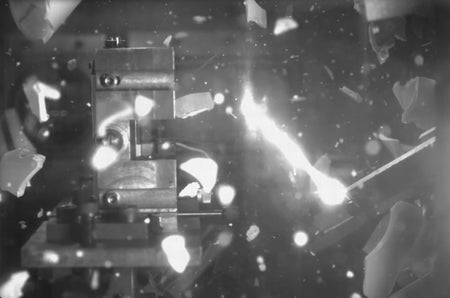 Slow motion video of capsule into a metal experimental setup and shattering