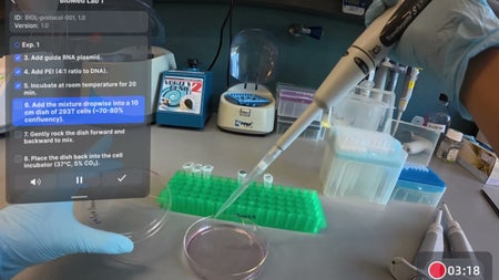 Person wearing blue lab gloves uses a pipette to add liquid dropwise into a small petri dish on a lab bench. A translucent on-screen protocol overlay lists steps for adding guide RNA plasmid and PEI to 293T cells. In the background are lab equipment including a vortex mixer, mini centrifuge, tube rack with microcentrifuge tubes, and pipette tip boxes. A timer in the corner shows 03:18.