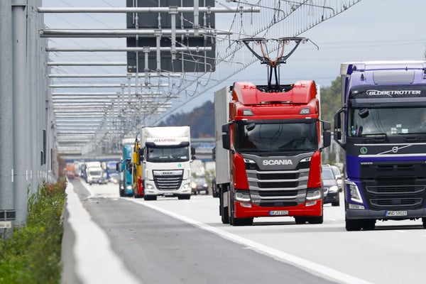 A Scania AB R450 cargo e-truck, second right, powered by overhead electrical power lines drives alongside other non-electric trucks on the A5 autobahn.