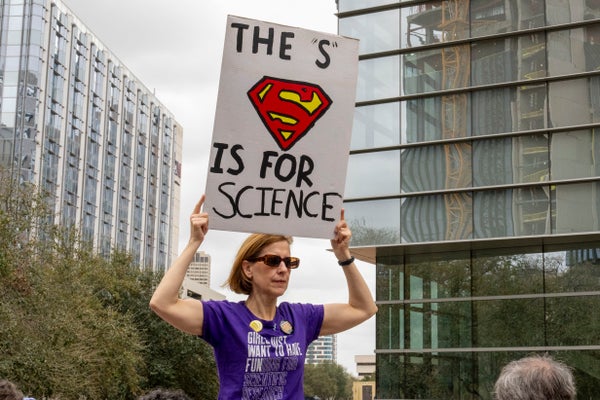 A woman holding an "S" is for Science sign