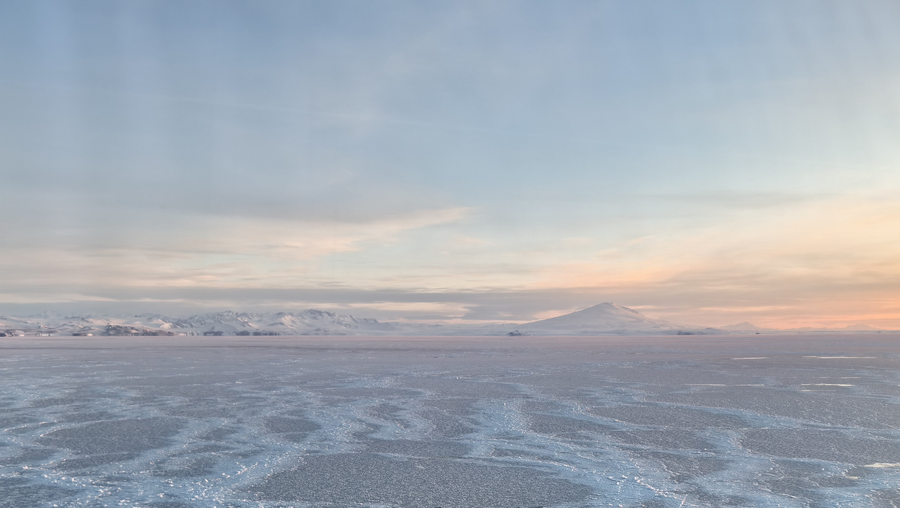 Partially frozen sea with snow-capped mountain in background