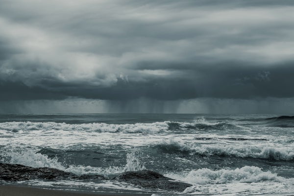 view of the splashing waves of the ocean with dark clouds in the sky