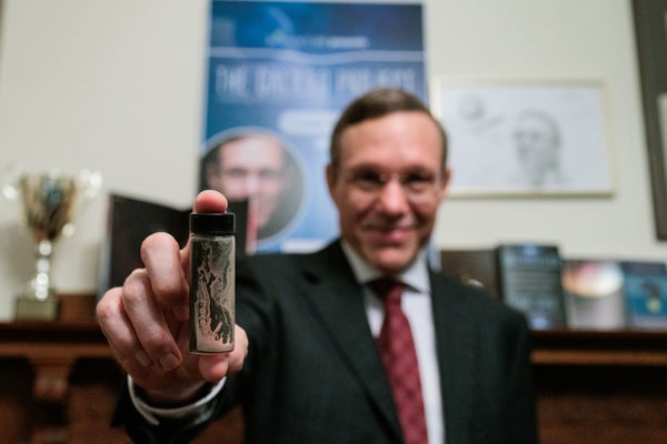 The Harvard University astrophysicist Avi Loeb smiles while displaying a small tube of material recovered from the floor of the Pacific Ocean