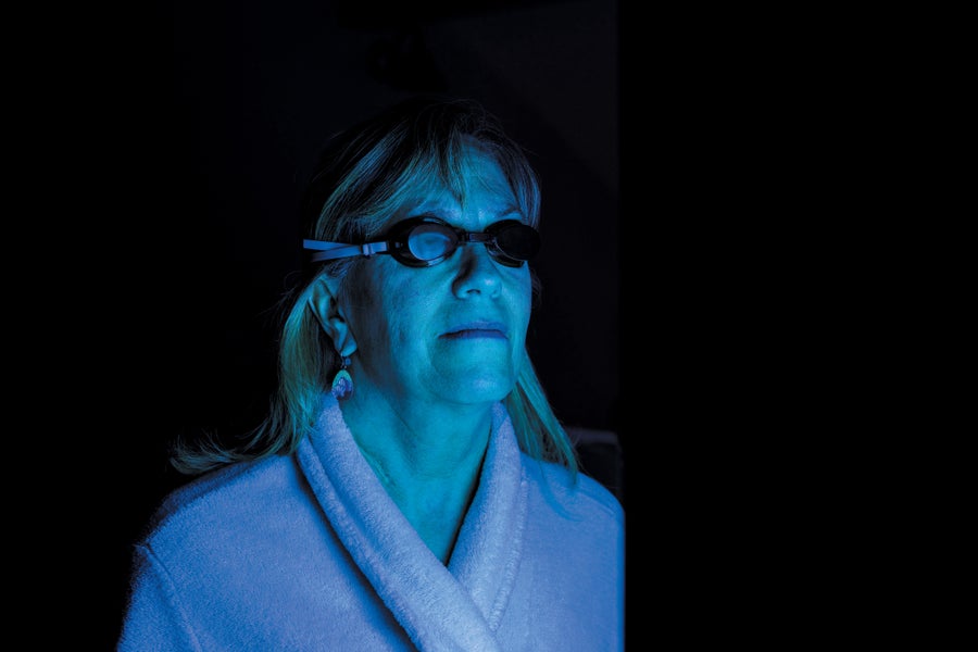Woman wearing goggles, blue light reflecting off her