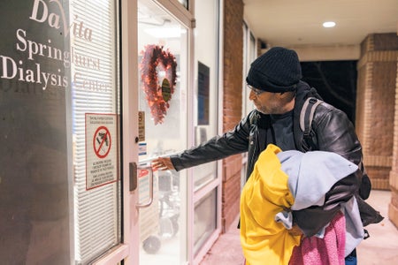 A man holding blankets, walking into a dialysis clinic.