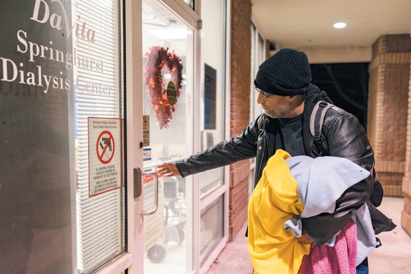 A man holding blankets, walking into a dialysis clinic.
