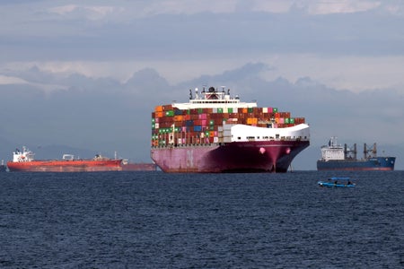 Cargo ship flanked by two other vessels on left and right.