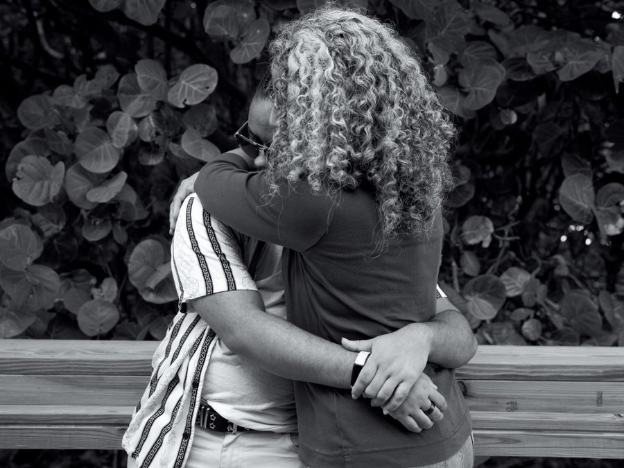 In a black and white photo, two people are hugging.
