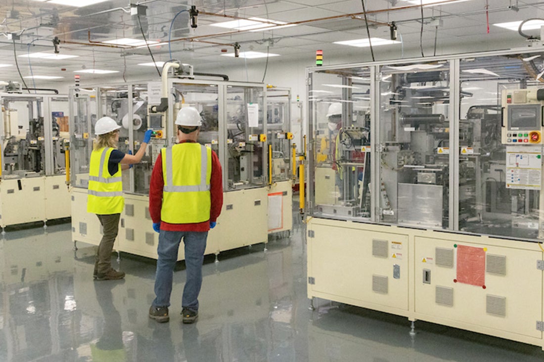 Two workers with yellow safety vests working in a facility