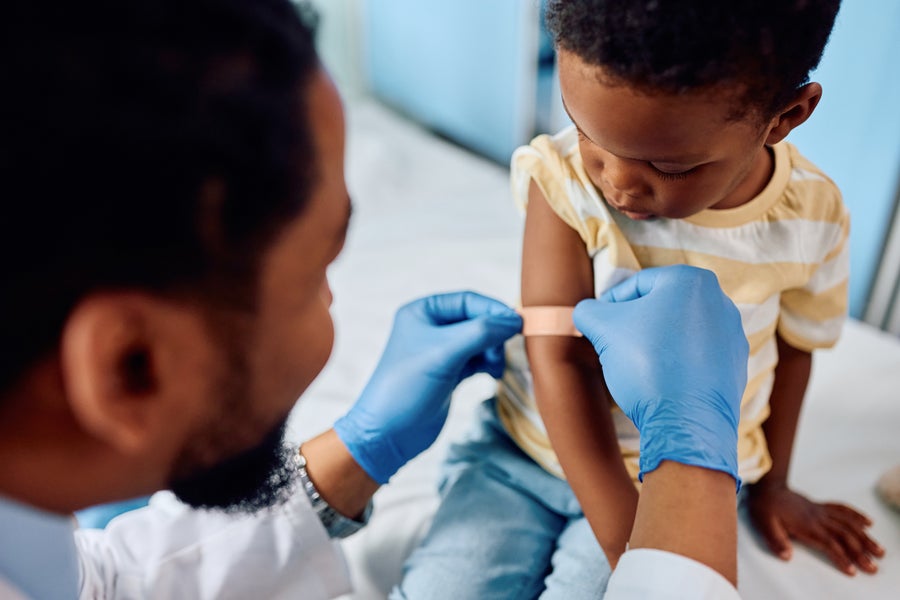 Close up of doctor applying adhesive bandage on a boy's arm after the vaccination at medical clinic