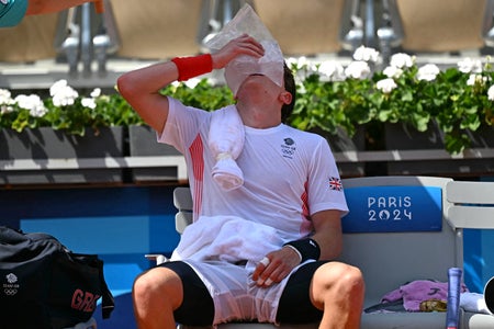 Tennis player sitting on bench with ice bag on his face.