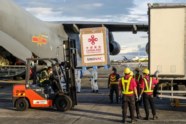 Ground crew workers at Phillipines' Villamor Airbase unload a cargo shipment on a palette containing China's Sinovac vaccine. On the package above the Sinovac vaccine, a second label reads "CHINA AID FOR SHARED FUTURE."