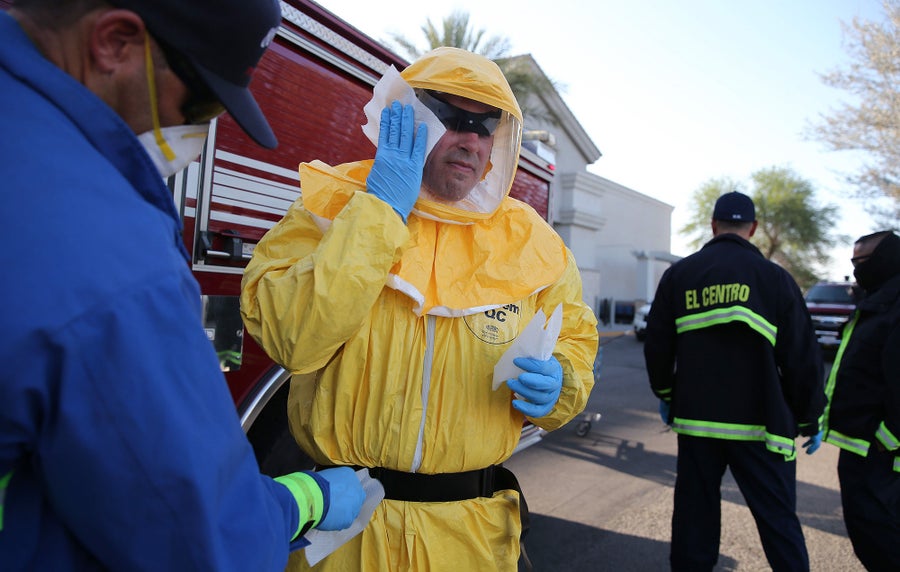 Firefighter in yellow protective suit wipes face mask with cloth