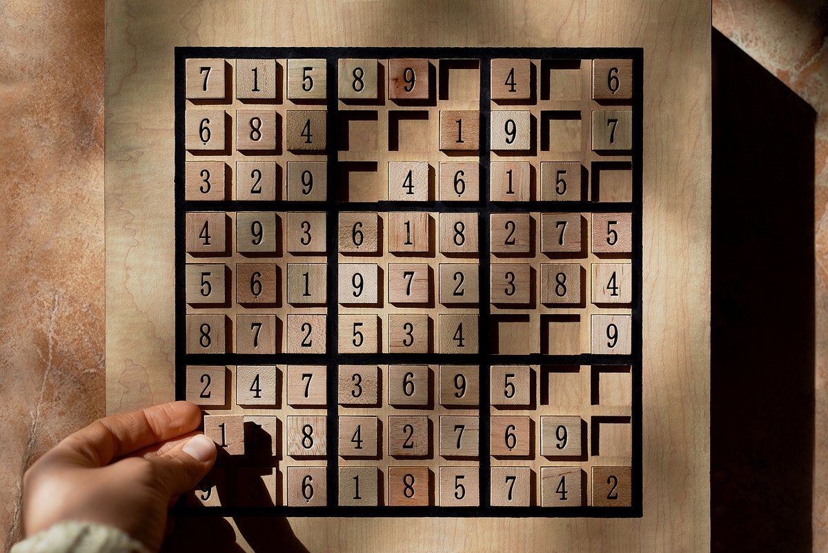 Playing a wood Sudoku game board with puzzle in progress in stock photo