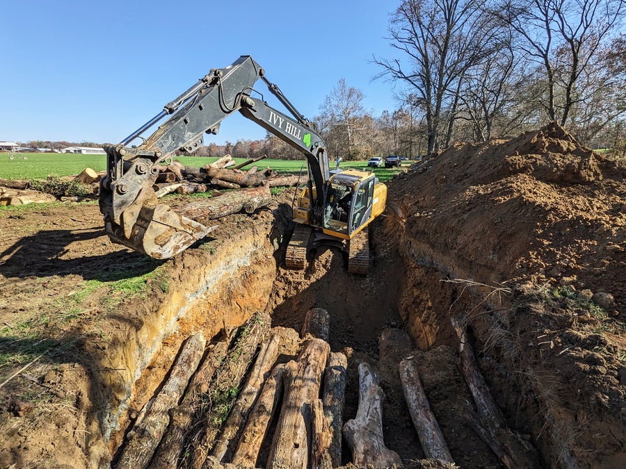 Log piles being buried with an excavator
