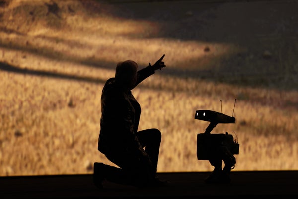 Silueta zakladatele a generálního ředitele Nvidie Jensena Huanga, jak mluví s robotem a ukazuje směrem k obloze