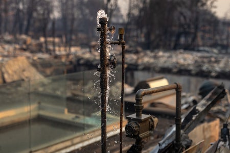 Water runs from a pipe of a destroyed home.