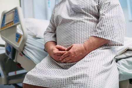 Close up of frightened patient in a hospital gown sitting on hospital bed.