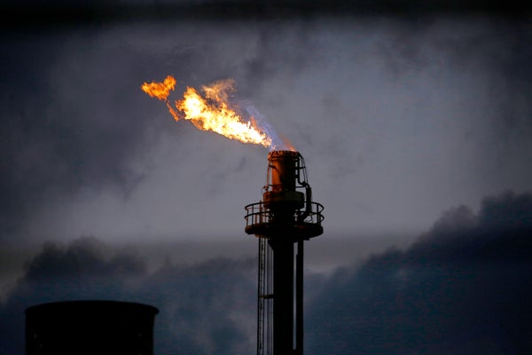 Flames from a flare stack at an oil refinery against a dark sky