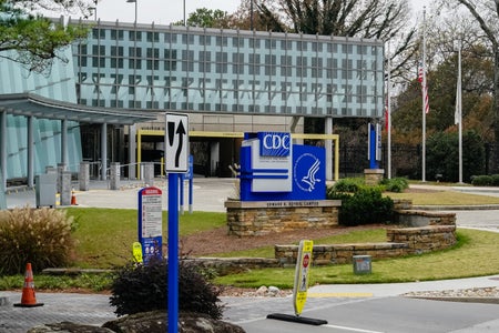 A glass-walled building entrance fronted by CDC signs