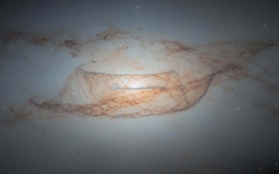 Lenticular galaxy NGC 4753 is featured with a bright white core and surrounding defined dust lanes around its nucleus, that predominantly appear dark brown in colour. A variety of faint stars fill the background of the image