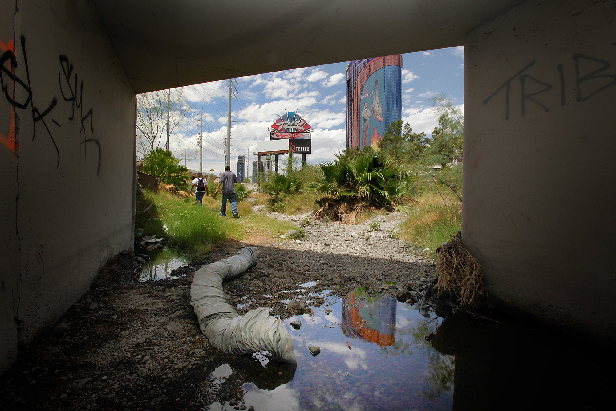 Houseless men walk out of a flood control tunnel under the city of Las Vegas near the Rio Hotel and Casino on June 26, 2009