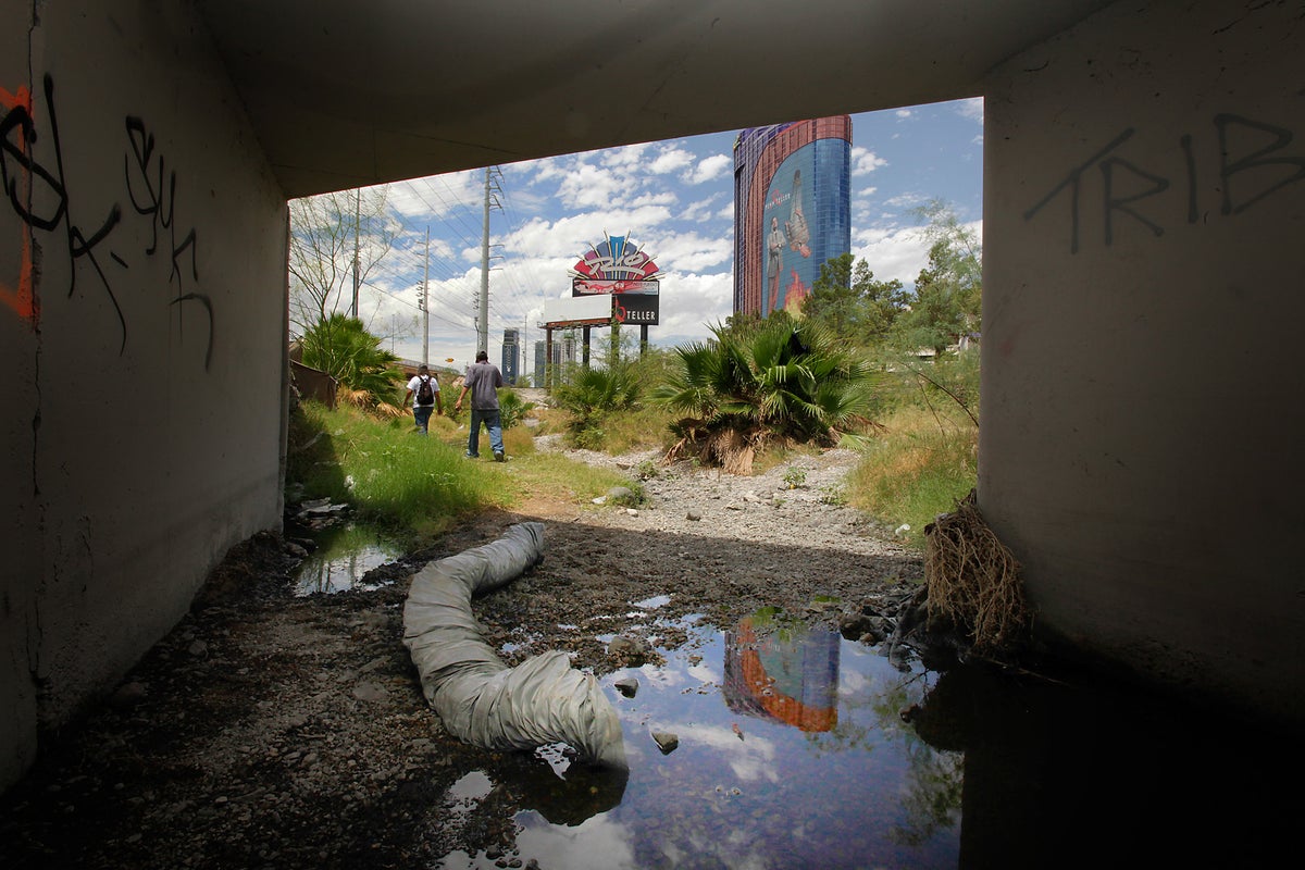 	Houseless men walk out of a flood control tunnel under the city of Las Vegas near the Rio Hotel and Casino on June 26, 2009