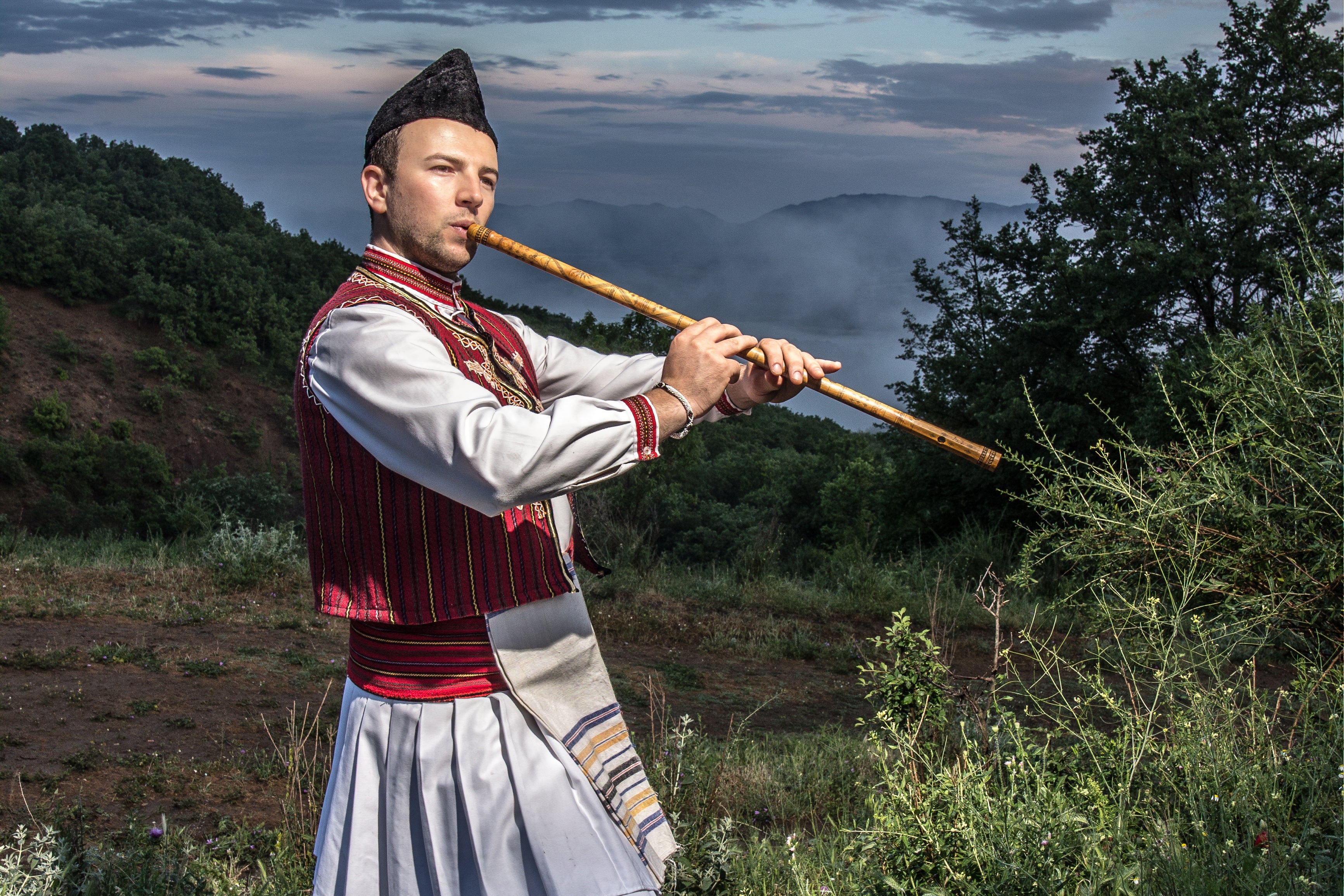 Study coauthor Aleksandar Arabadjiev of Macedonia singing and playing a traditional instrument while standing outside during dusk