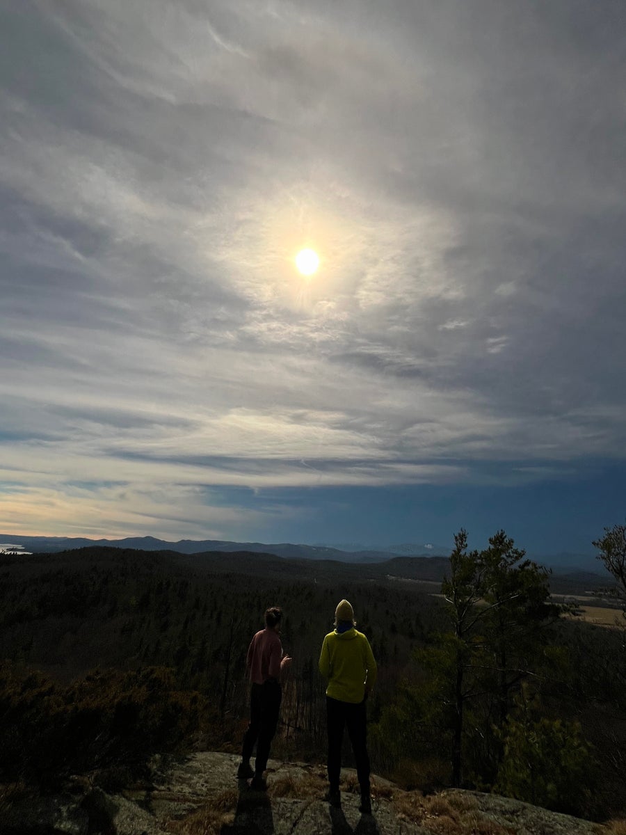 Backview of two people on mountain ( yellow sweater) watching the eclipse in