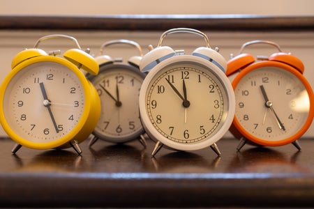 Alarm clocks of different colors showing different times.
