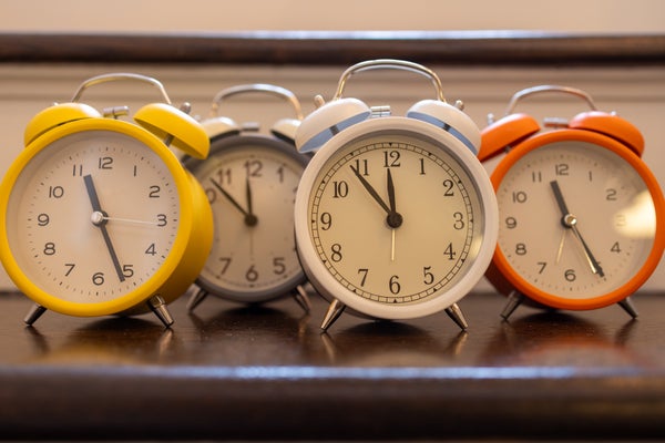 Alarm clocks of different colors showing different times.