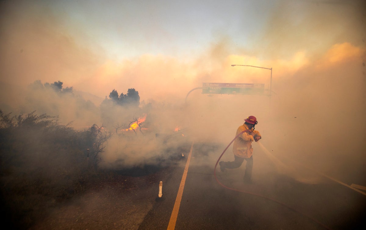 Firefighter with hose in heavy smoke.