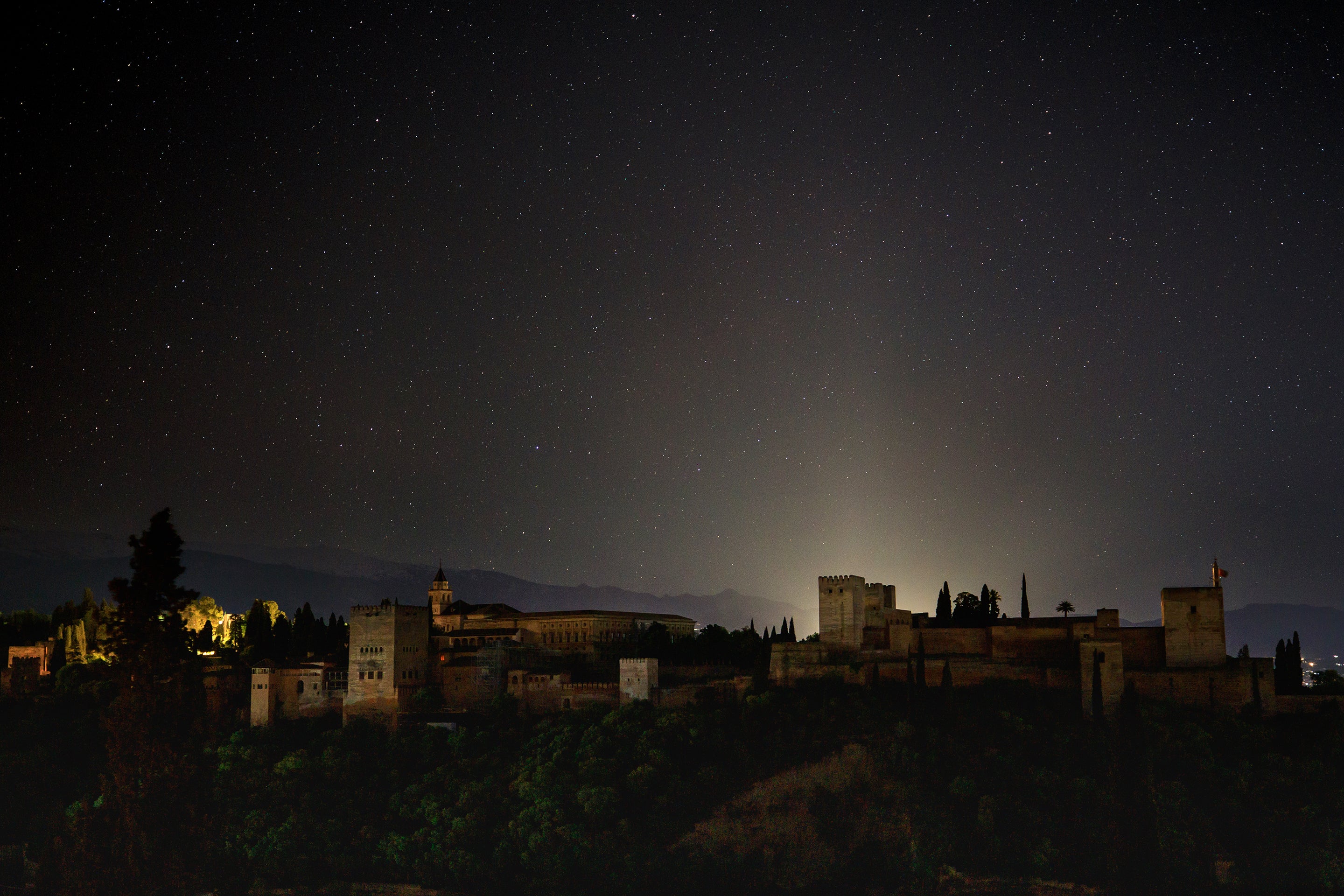 A view of the starry Alhambra sky and the darkened landscape of Granada, Spain during a blackout below as a widespread power outage strikes Spain and Portugal on April 28, 2025