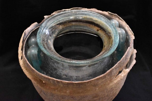 Photographie de l'ouverture supérieure d'une urne ancienne, vieille de plus de 2000 ans, sur fond noir