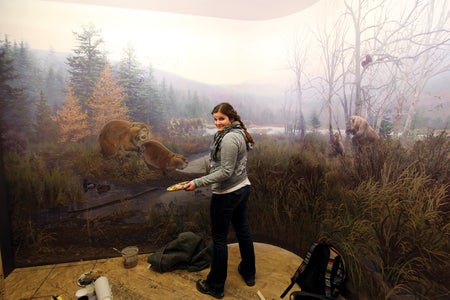 Image of Beth Zaiken in front of a pre-historic landscape