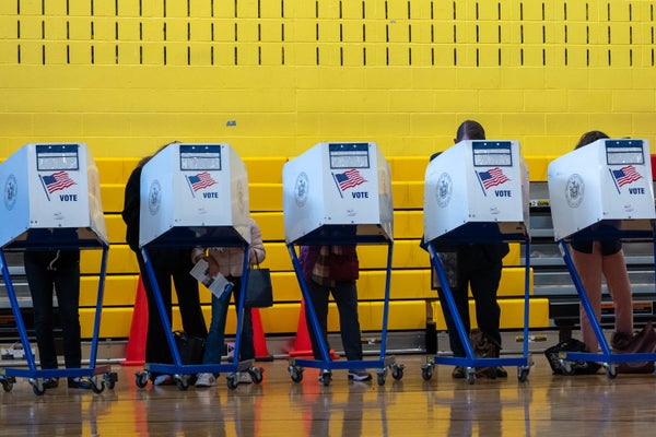 Uma foto de pessoas votando em uma assembleia de voto.