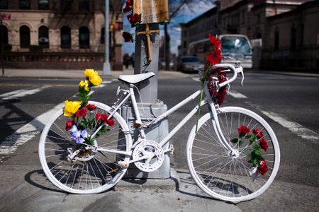 A white painted bike adorned with flowers on a street corner.