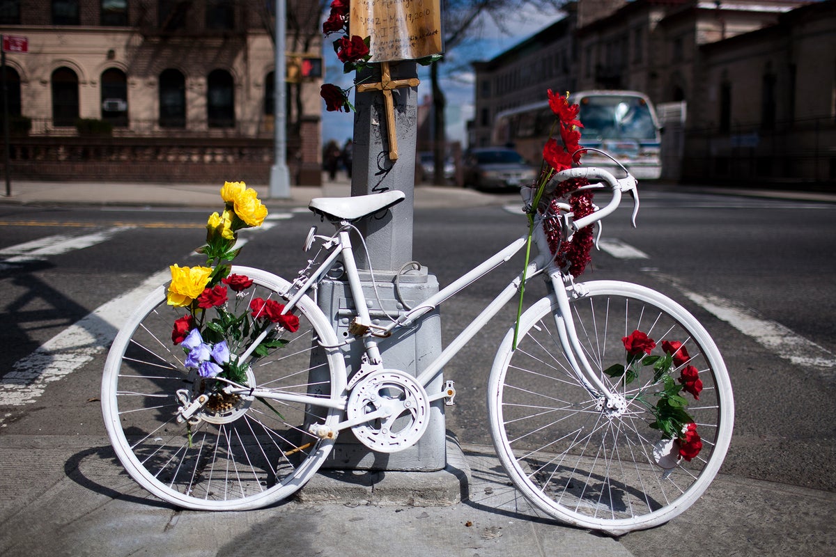 A white painted bike adorned with flowers on a street corner.