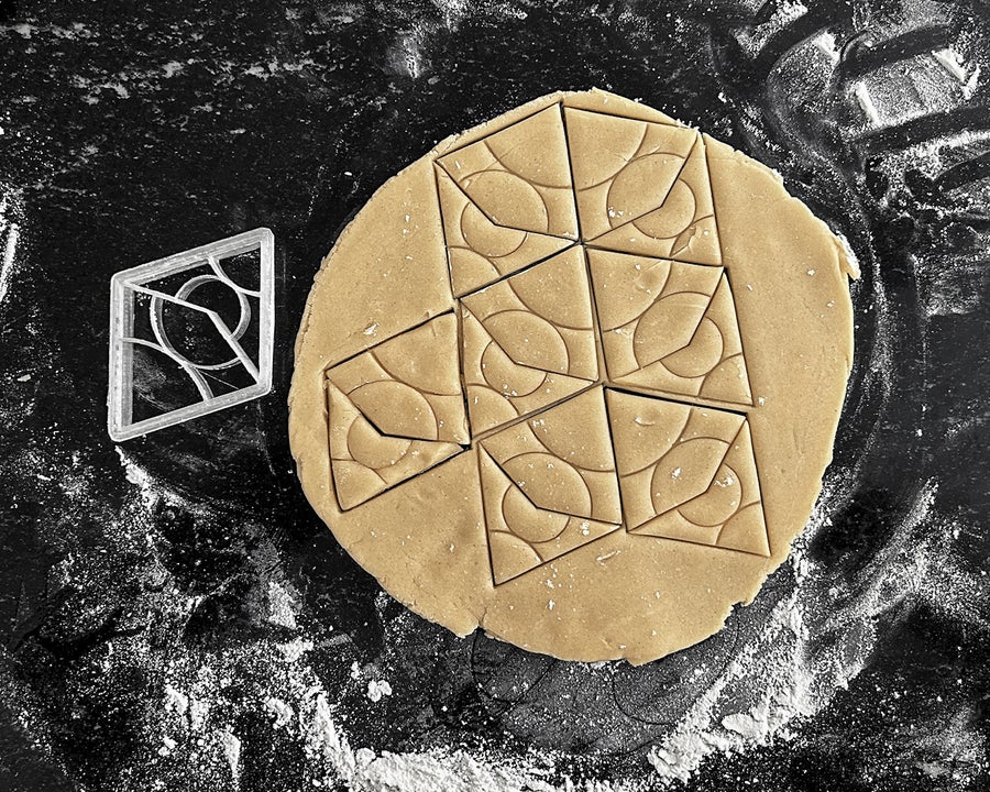 Cookie dough rolled out onto a counter, stamped with a 3D printed diamond shaped cookie cutter in a tessellated pattern