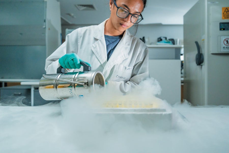 A scientist in a white coat and glasses prepares to analyze DNA in a lab