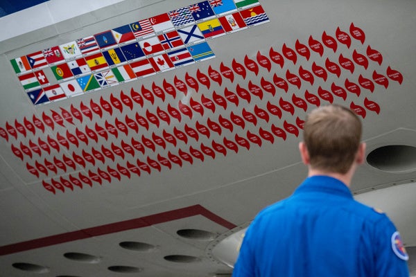 Close up view of stickers from previous hurricane missions adorn the side as a crew member walks past "Kermit", a National Oceanic and Atmospheric Administration (NOAA) WP-3D Orion hurricane hunter aircraft