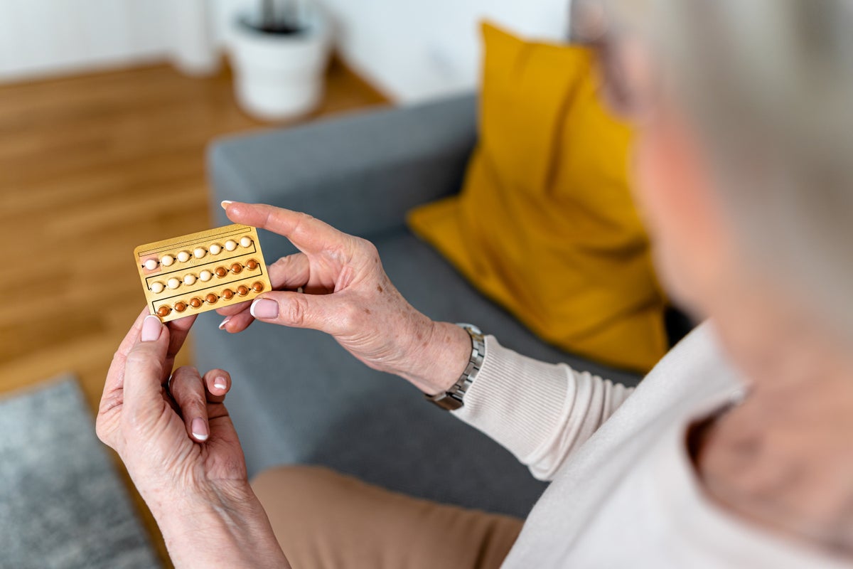 An older woman holding a pack of hormone therapy pills